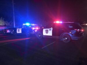 Image of two police cars in the dark with flashing red and blue lights.